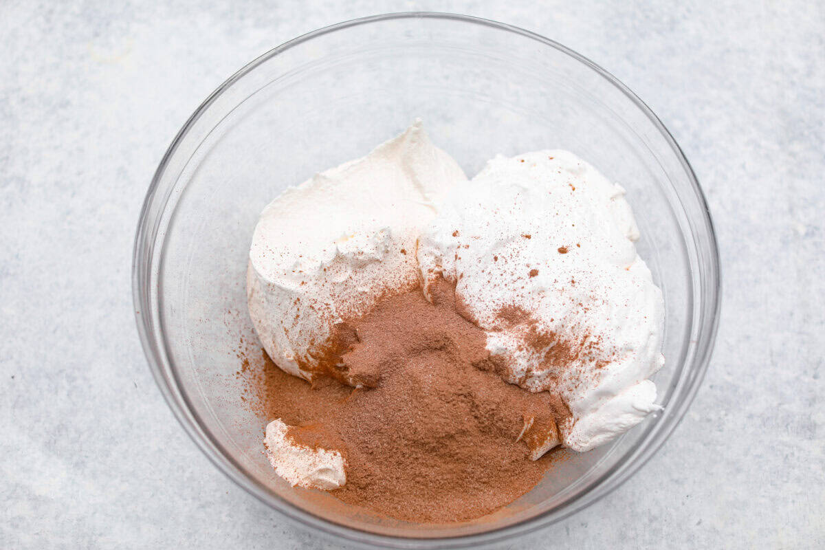 This hot cocoa dip recipe has only 3 ingredients and comes together in 5 minutes. It's chocolatey, fluffy, sweet, and creamy. It's perfect to take to holiday parties or cozy winter gatherings. Overhead shot of ingredients in a glass bowl.