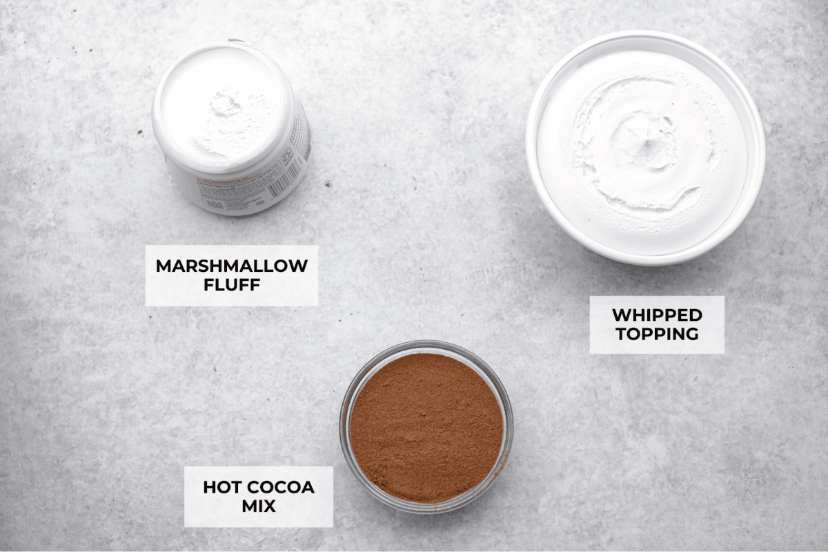 This hot cocoa dip recipe has only 3 ingredients and comes together in 5 minutes. It's chocolatey, fluffy, sweet, and creamy. It's perfect to take to holiday parties or cozy winter gatherings. Overhead shot of labeled ingredients.