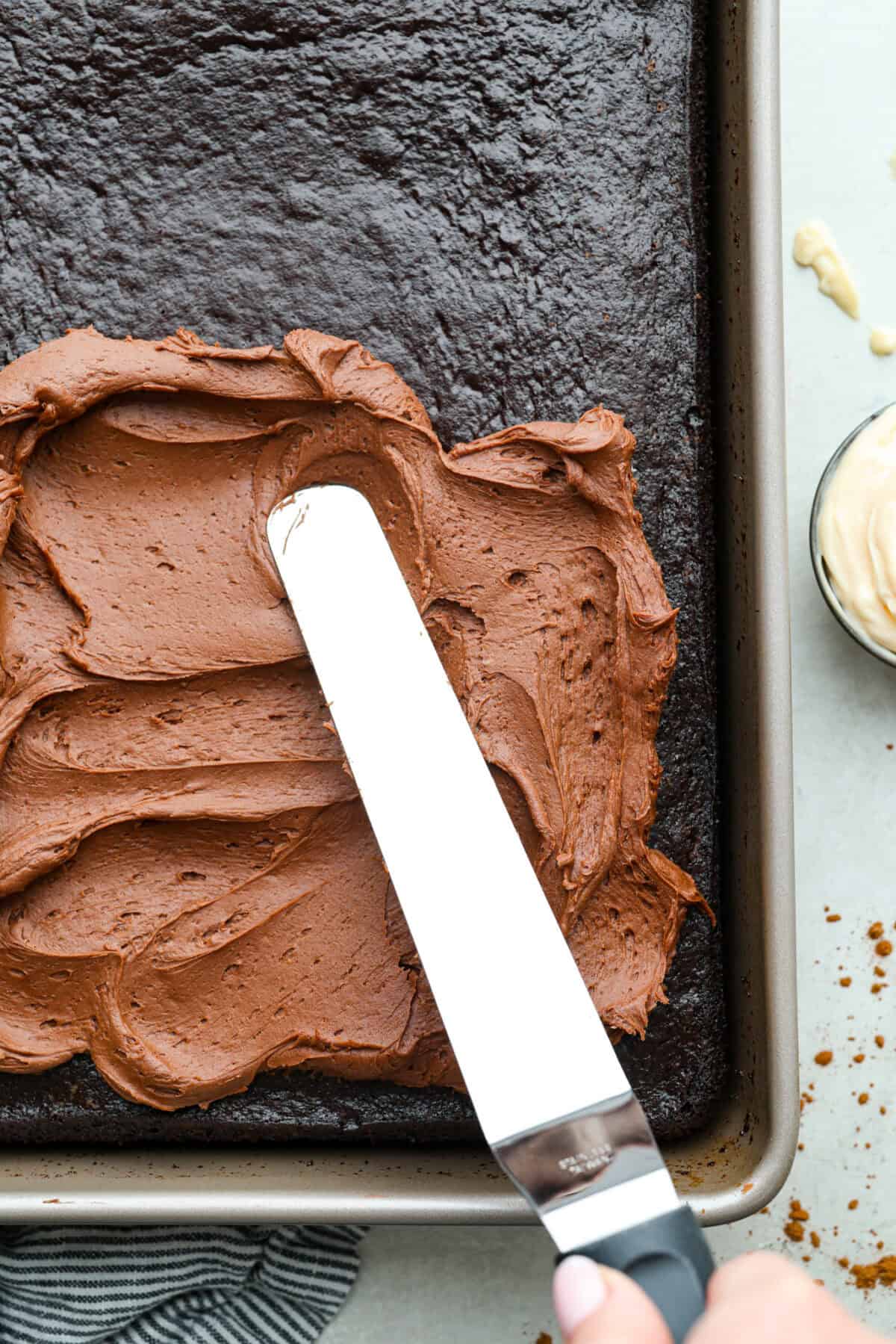 Chocolate Mayonnaise Cake is a rich, moist, and decadent dessert that’s super easy to make! The mayonnaise adds extra moisture and creates a soft, tender crumb. Whether for a special occasion or just because it's sure to impress! Overhead shot of someone frosting the chocolate mayonnaise cake with chocolate buttercream frosting.